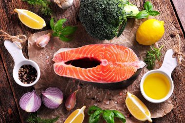 Brokoli, limon, sarımsak, kırmızı soğan, dereotu, zeytin yağı ve Himalaya tuz eski ahşap arka plan üzerinde Çiğ somon. Sağlıklı gıda.
