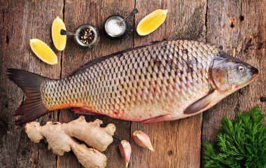 Limon, zencefil, sarımsak, dereotu, deniz tuzu ve eski ahşap zemin üzerine biber ile taze çiğ vahşi sazan.