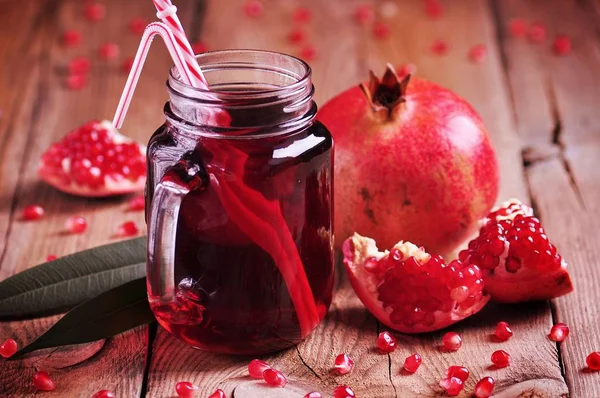 Natural pomegranate juice in a pot on the old wooden background. Healthy food. — Stock Photo, Image