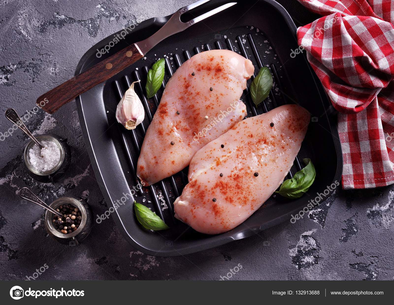 Raw chicken breast with smoked paprika, sea salt and pepper on a cast