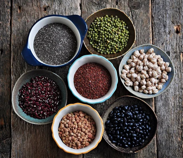 Healthy food - lentils, chickpeas, black beans, red beans, peas, quinoa and chia seeds on old wooden background.