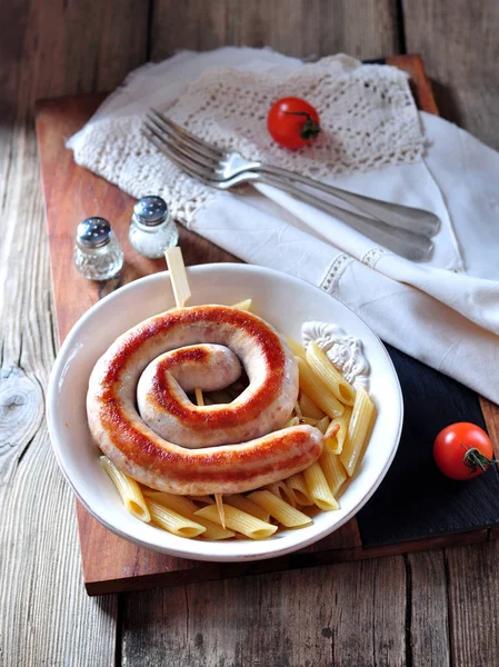 Жареная колбаса с вареной пастой в оливковом масле на старом деревянном фоне . — стоковое фото