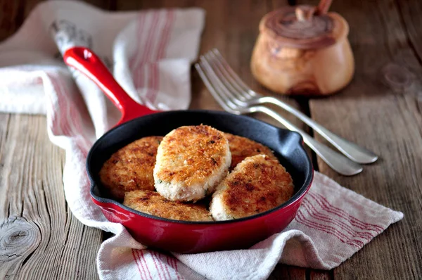 Hühnerschnitzel (Burger) in einer gusseisernen Pfanne vor altem Holzhintergrund. — Stockfoto