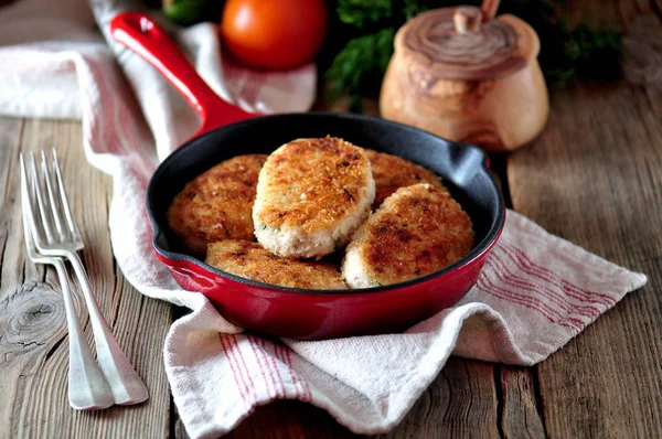 Chicken cutlets( burgers) in a cast iron skillet over an old wooden background. — Stock Photo, Image