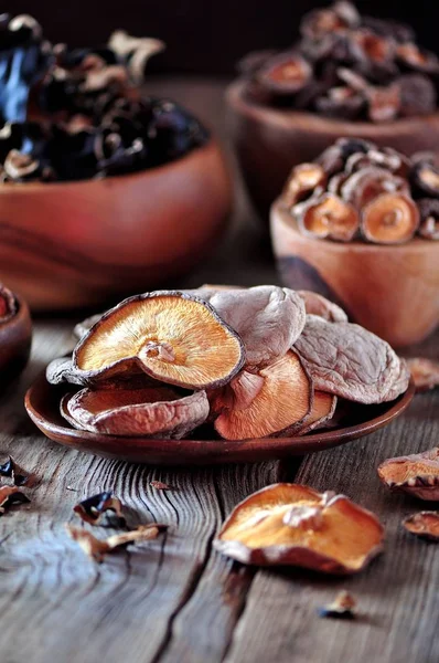Различные органические сушеные китайские грибы в деревянной чаше на старом деревянном фоне . — стоковое фото