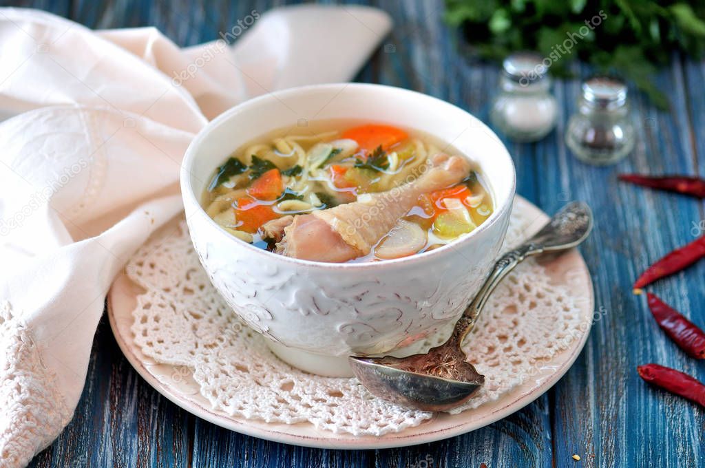 Soup with homemade noodles and organic chicken with carrots, root and leaves of parsley, onion and celery sticks.