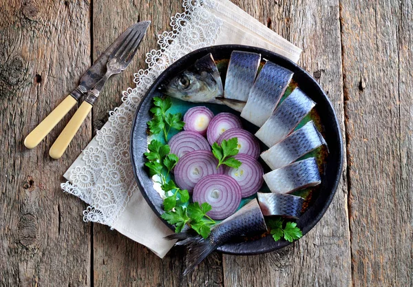 Delicious salted herring with red onion, salt and pepper on the old wooden background. Rustic style. — Stock Photo, Image