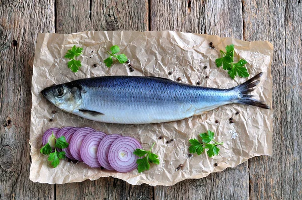 Delicioso arenque salado con cebolla roja, sal y pimienta sobre el fondo de madera vieja. Estilo rústico . — Foto de Stock