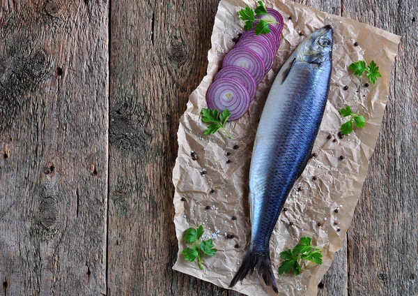 Delicioso arenque salado con cebolla roja, sal y pimienta sobre el fondo de madera vieja. Estilo rústico . — Foto de Stock