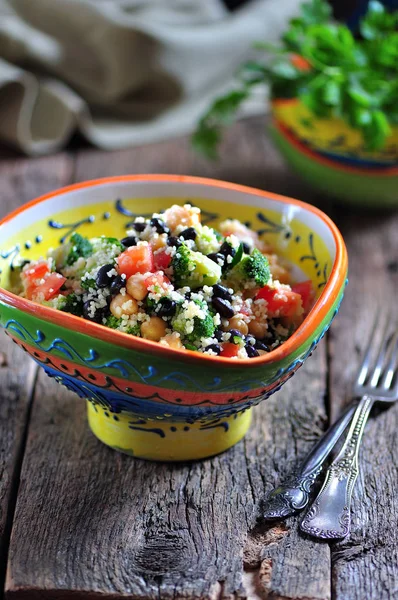 Salada saudável de grão de bico, cuscuz, feijão preto com tomate, brócolis, salsa, azeite e sal marinho . — Fotografia de Stock