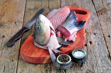 Fresh raw fish head and bones for soup, broth or sauce on a wooden background. clipart