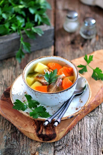 Sopa de peixe com batatas, cenouras e salsa no velho fundo de madeira . — Fotografia de Stock