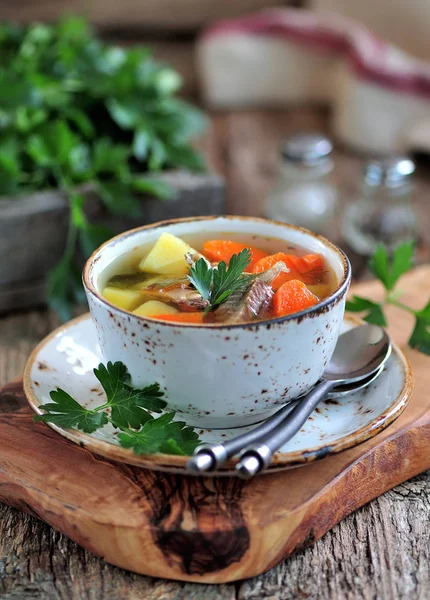 Fish soup with potatoes, carrots and parsley on the old wooden background. — Stock Photo, Image