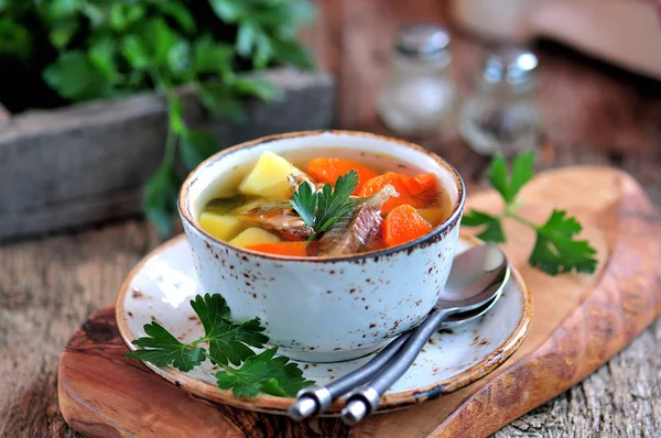 Sopa de peixe com batatas, cenouras e salsa no velho fundo de madeira . — Fotografia de Stock