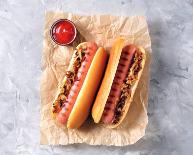 Çıtır soğan ve ketçap ile iki sosisli sandviç.