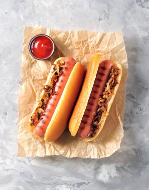 Çıtır soğan ve ketçap ile iki sosisli sandviç.