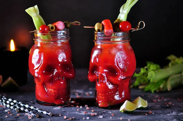 Bloody Mary cocktail in glasses-skull with celery sticks, pink salt, lime and canapes from canned vegetables. — Stock Photo, Image