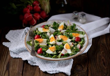 Spring green salad from organic radish, wild garlic with boiled eggs, olive oil and parmesan. clipart