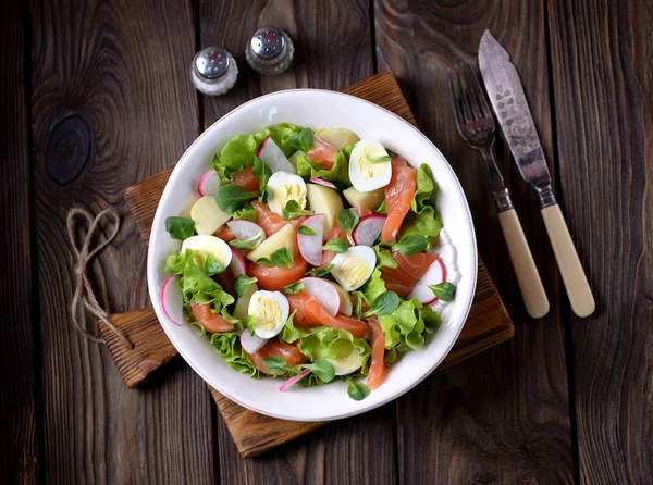 Salată din somon ușor sărat, cartofi fierți, ouă de prepeliță cu castraveți și ridiche . — Fotografie, imagine de stoc