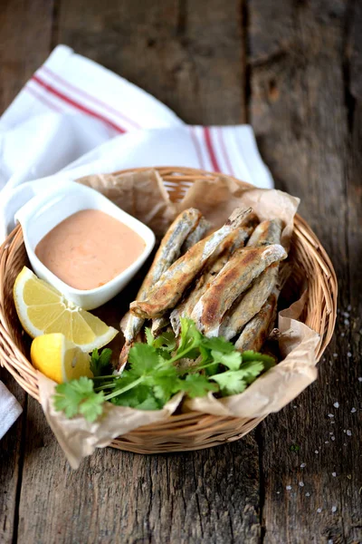 Small capelin fish baked in an oven without butter with sauce and lemon. — Stock Photo, Image