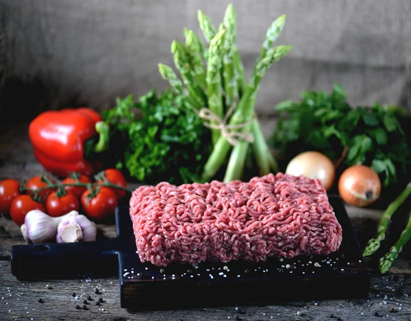 Carne moída crua fresca com legumes frescos em um fundo de madeira velho. Estilo rústico . — Fotografia de Stock