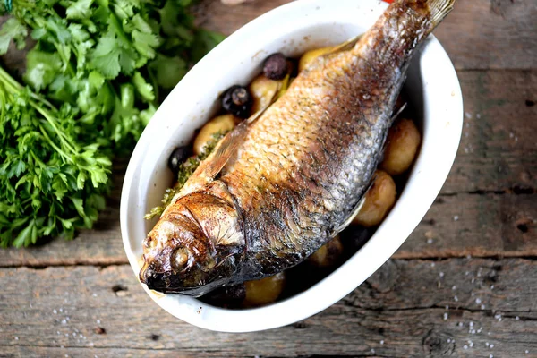 Baked golden fish with carp with potatoes and mushrooms on an old wooden background. Rustic style. — Stock Photo, Image