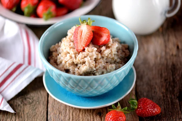 Harina de avena con fresas frescas y leche sobre un fondo de madera vieja. Desayuno saludable. Alimento saludable . — Foto de Stock