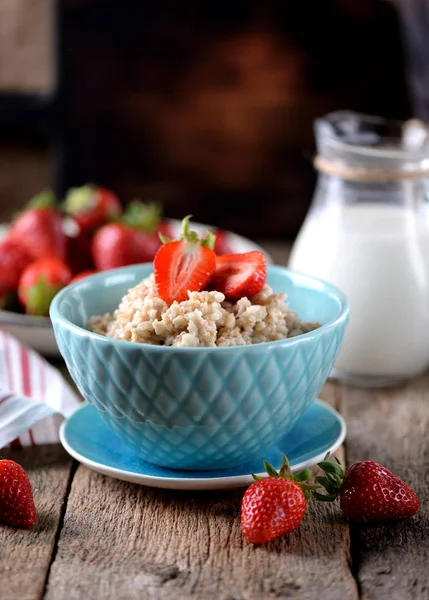 Harina de avena con fresas frescas y leche sobre un fondo de madera vieja. Desayuno saludable. Alimento saludable . — Foto de Stock