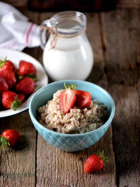 Haferflocken mit frischen Erdbeeren und Milch auf altem Holzgrund. gesundes Frühstück. gesunde Ernährung. — Stockfoto