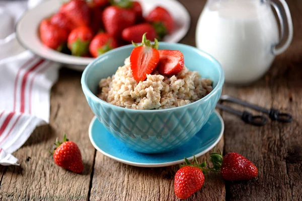 Haferflocken mit frischen Erdbeeren und Milch auf altem Holzgrund. gesundes Frühstück. gesunde Ernährung. — Stockfoto