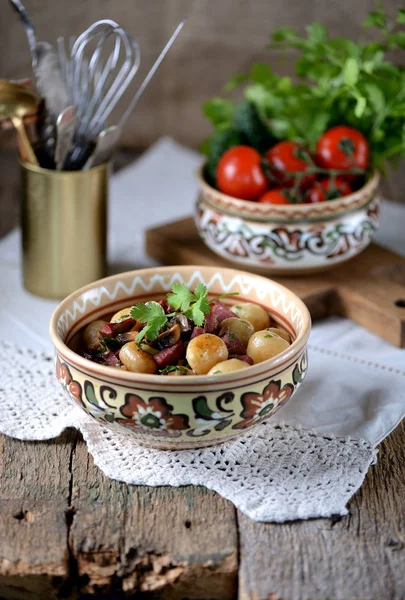 Маленький картофель жареный с колбасой, грибами и луком на старом деревянном фоне. Сельский стиль . — стоковое фото