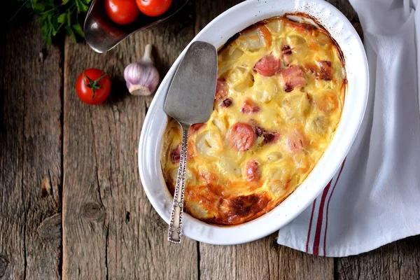 Caçarola de batata com salsichas, cebolas e queijo em um fundo de madeira velho. Estilo rústico . — Fotografia de Stock