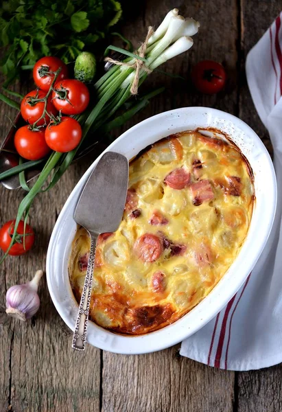 Cazuela de patatas con salchichas, cebollas y queso sobre un fondo de madera vieja. Estilo rústico . —  Fotos de Stock