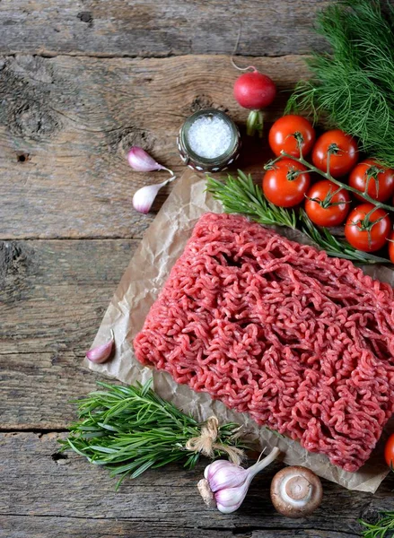 Carne fresca crua picada com alecrim, endro, alho e tomate cereja em um fundo de madeira velho. Espaço de cópia , — Fotografia de Stock