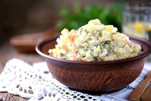 Traditional Russian salad Olivier on an old wooden background. Russian kitchen. Rustic style.