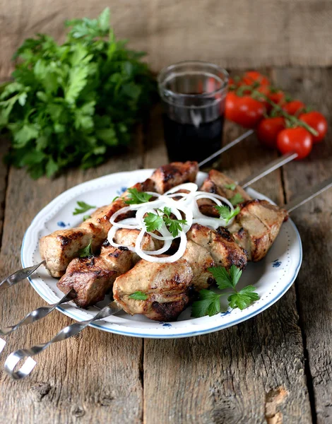 Huis shish kebab van varkensvlees op spiesjes met ingemaakte UI en peterselie op een oude houten achtergrond. — Stockfoto