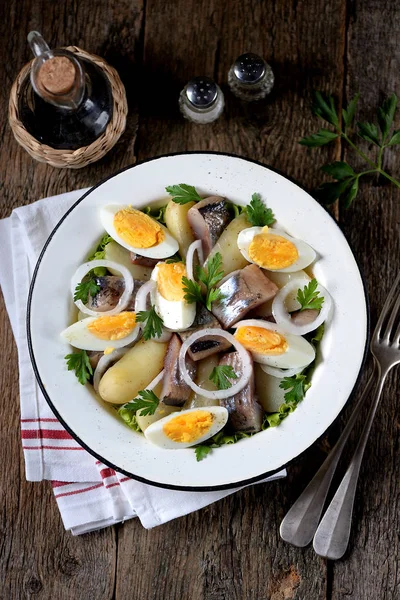 Salad from light-salted herring, boiled potatoes, eggs and onions with olive oil and lemon juice. Rustic style. — Stock Photo, Image