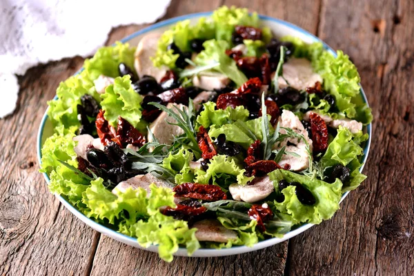 Салат з вареної курячої грудки, сушених на сонці помідорів, оливок, руколи та салату з оливковою олією та винним оцтом . — стокове фото