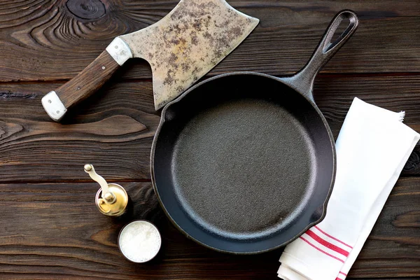 Padella in ghisa con sale e pepe su fondo di legno . — Foto Stock