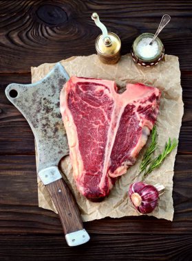 Sarımsak ve biberiye eski bir ahşap zemin üzerinde ham t-bone biftek. Rustik tarzı.
