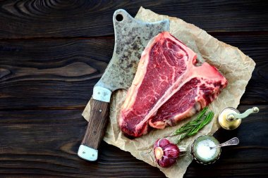 Sarımsak ve biberiye eski bir ahşap zemin üzerinde ham t-bone biftek. Rustik tarzı.