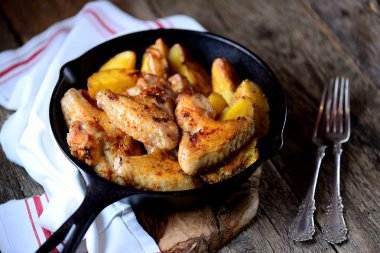 Baharatlar ve aromatik otlar - fesleğen, biberiye, dereotu ve sarımsaklı patates ile pişmiş tavuk kanadı.