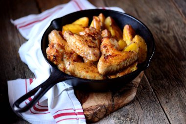 Baharatlar ve aromatik otlar - fesleğen, biberiye, dereotu ve sarımsaklı patates ile pişmiş tavuk kanadı.