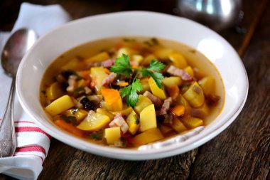 Patates, havuç, soğan, mantar, maydanoz ve pastırma eski bir ahşap zemin üzerine sarı kabak çorbası.