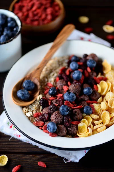 Healthy breakfast of cornflakes, chocolate balls, oatmeal, goji berries and fresh blueberries. — Stock Photo, Image