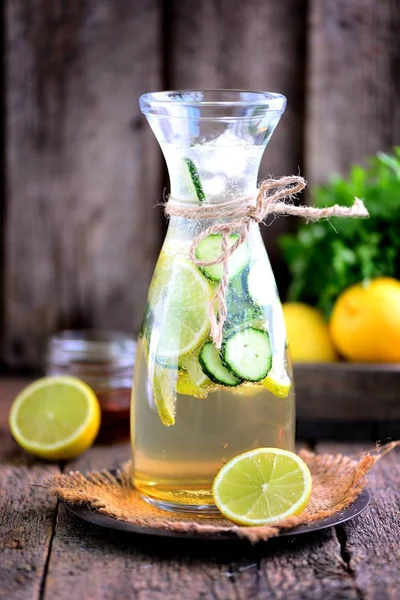 Sana limonata fatta in casa a base di lime, cetriolo e sciroppo di agave con ghiaccio. Stile rustico, vecchio sfondo in legno . — Foto Stock