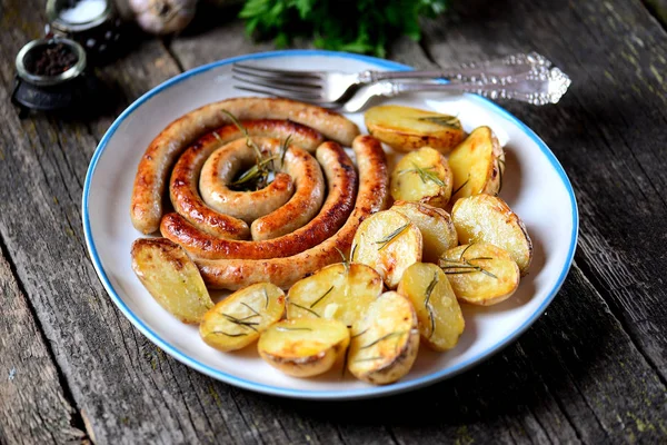 Sosis, biberiye ve eski bir ahşap zemin üzerine sarımsak fırında patates. Rustik gıda. — Stok fotoğraf