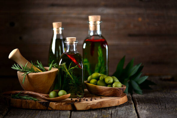 Organic olive oil with spices and herbs on an old wooden background. Healthy food.