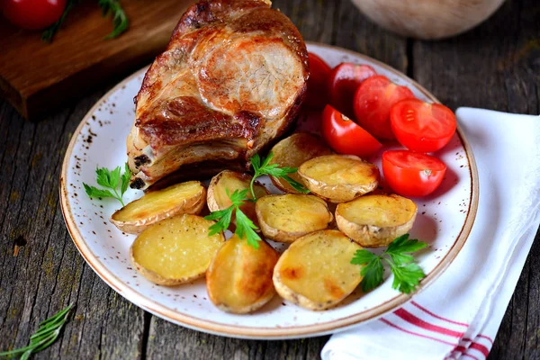 Grilovaná vepřová kotleta s pečenými brambory a cherry rajčaty. — Stock fotografie