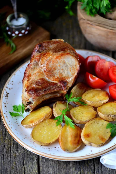 Chuleta de cerdo a la parrilla con papas al horno y tomates cherry . —  Fotos de Stock
